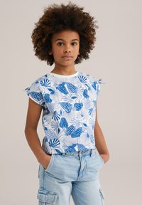 Top blanco de manga corta con patrones abstractos de hojas azules, tela texturizada y lazos recogidos en las mangas; combinado con pantalones cortos cargo de lavado claro.