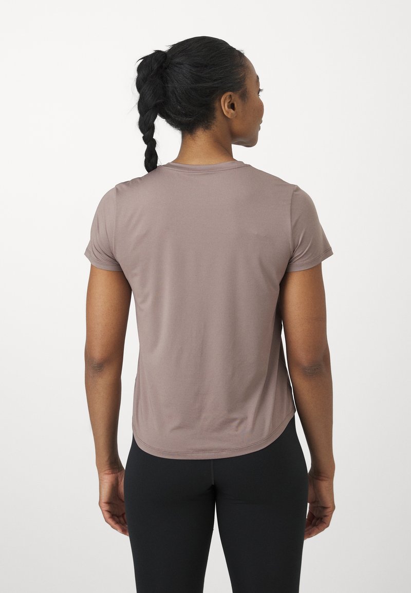 Korte mauve t-shirt met ronde hals en een licht gebogen zoom, gecombineerd met zwarte leggings. Glad materiaal en fitted silhouet.