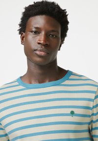 Gestreepte t-shirt in roomkleur en blauw, met een ronde halslijn en klein groen boompje logo op de linkerborst. Zachte katoenen stof.