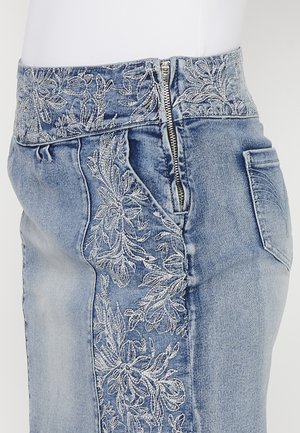 Denimrock mit hohem Bund, versehen mit silberner Blumenstickerei auf der linken Seite, Reißverschluss und einer einzelnen Gesäßtasche. Hellblaue Farbe.