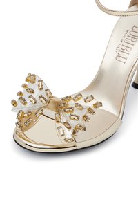 Goldene High-Heel-Sandale mit durchsichtiger Riemen und großer Schleife, verziert mit klaren und goldenen rechteckigen Juwelen, mit glänzender Oberfläche.