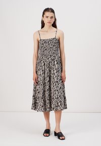 Rochie midi florală alb-negru cu bretele subțiri, bust plisat și fustă fluidă. Purtați cu sandale negre dintr-o singură bucată.