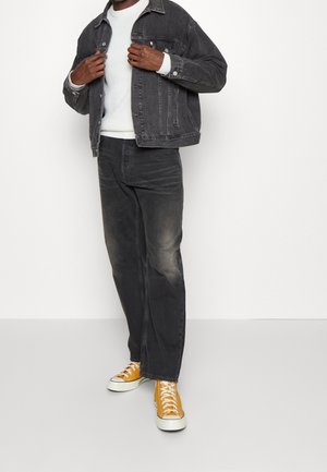 Grå denimbukse over en hvid strikket sweater, parret med falmede sorte jeans og lyse gule sneakers. Minimalistisk design, klassisk pasform.