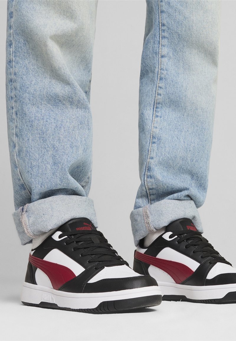 Černobílé tenisky s červenými akcenty, s hladkým koženým svrškem, kulatou špičkou a gumovou podrážkou. Nosit s bledými rozrolovanými džíny.