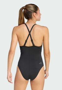 Černé jednodílné plavky s designem závodního zadního dílu, nastavitelnými ramínky a decentním logem v pravém dolním rohu. Hladká, elastická tkanina.