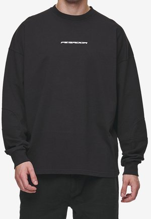 Černá mikina s dlouhým rukávem vyrobená z bavlny, s kulatým výstřihem, spadlými rameny a bílým logem potištěným na hrudi.