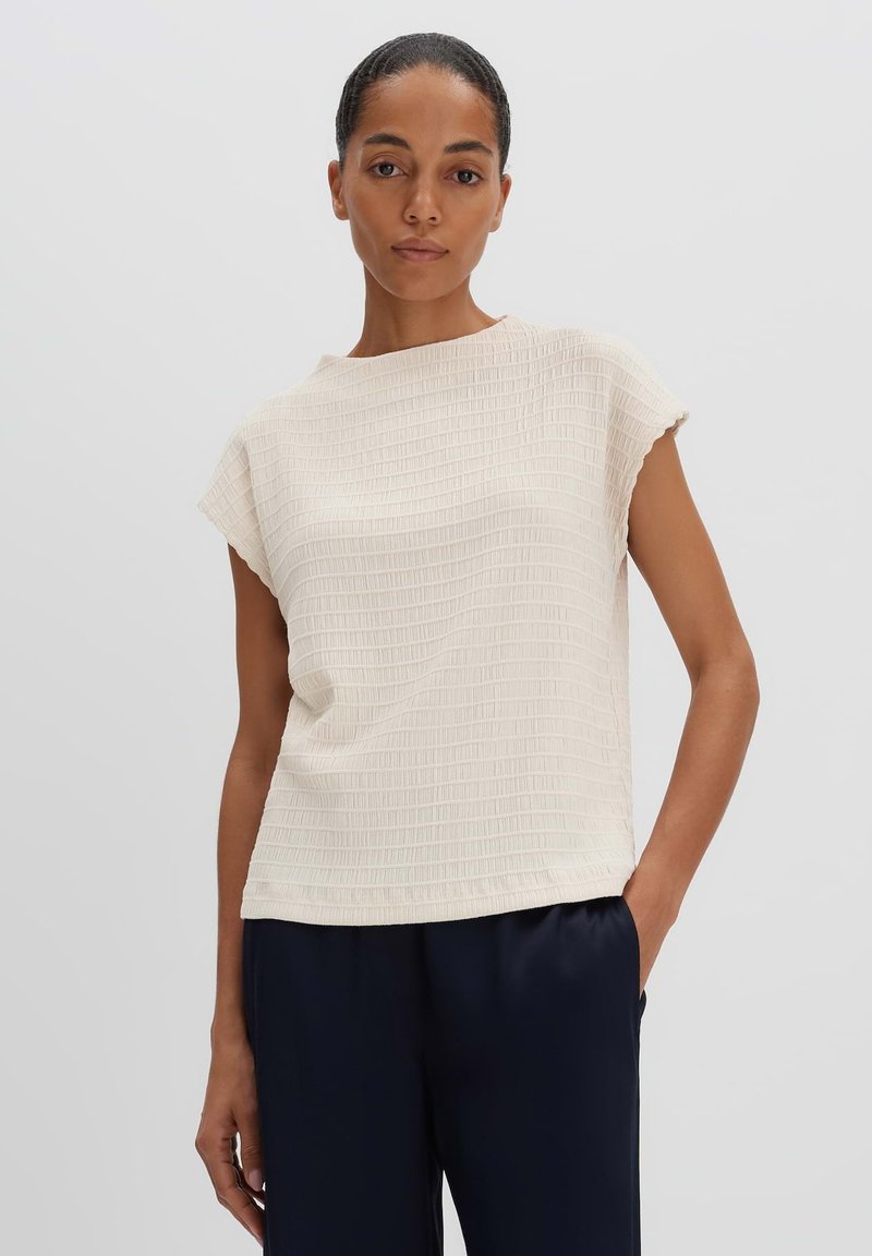 Light beige top featuring a textured grid pattern, short sleeves, and a relaxed fit. The design has a round neckline for comfort.