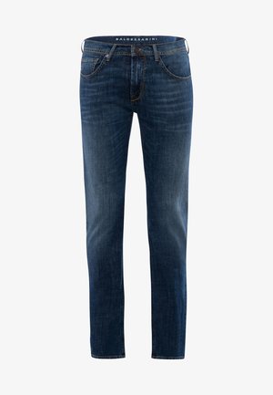 Helle graue Langarmbluse mit einem knöpfbaren Kragen, kombiniert mit dunkelblauen geraden Jeans und braunen Schuhen mit dekorativen Hardware-Details.