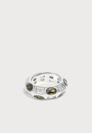 Silver ring with alternating green oval and round gemstones and clear rectangular gemstones set around the band on a plain background.