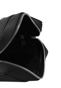 Zwart etui met ritssluiting, een gestructureerde buitenkant en een gladde binnenkant. Voorzien van een zilverkleurige rits en een eenvoudige, afgeronde vorm. Geen zichtbare logo's.