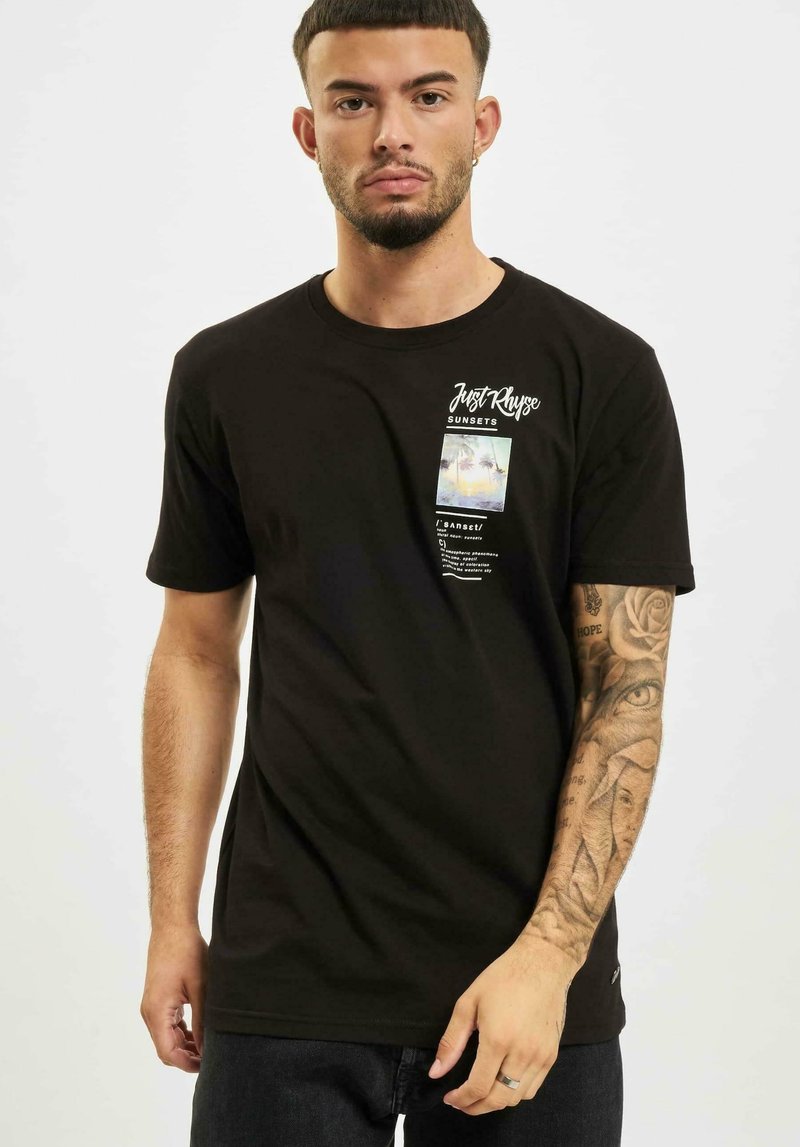Camiseta de algodón negra con un estampado gráfico que incluye palmeras, elementos de texto y un diseño rectangular. Mangas cortas y cuello redondo.
