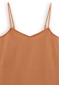 Camisole couleur rouille avec une surface texturée, dotée de fines bretelles ajustables et d'un décolleté en V. Tissu lisse et design ajusté.