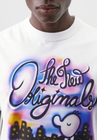 Weißes Baumwoll-T-Shirt mit einem bunten Grafikdesign, das den Text "The New Originals" in stilisierter Schriftart und einer Cartoonfigur zeigt.