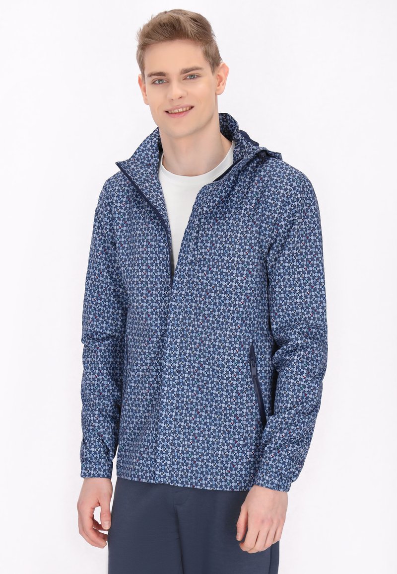Jachetă bleu marin cu un model floral, cu fermoar în față, glugă și buzunare laterale. Fabricată dintr-un material ușor, texturat.