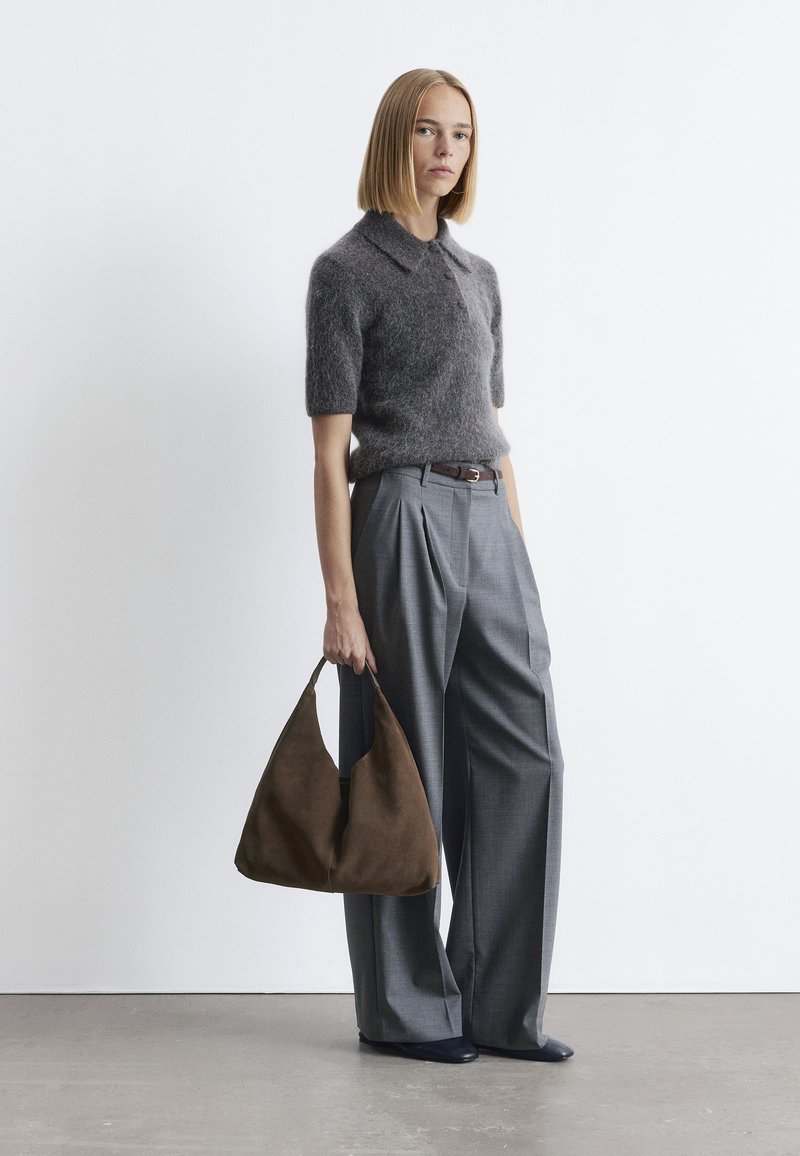 Graues, flauschiges Strick-Poloshirt, maßgeschneiderte graue Faltenhose, braune Wildleder-Handtasche und dunkle Schuhe. Minimalistisches Design mit weichen Texturen.