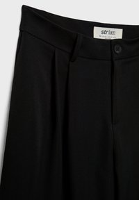 Pantalon noir taille haute, coupe ajustée, avec passants de ceinture, fermeture à boutons sur le devant et plis sous la taille.