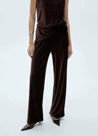 Bordeaux ribbed twee-delig outfit met een losse top met gedrapeerde details en wijde broekspijpen, gecombineerd met puntige zwarte hakken.