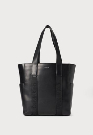 Svart lær tote bag med doble håndtak, med preget logo detaljer og sidelommer for ekstra lagring. Glatt finish, strukturert design.