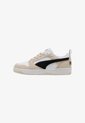 Deportivas beige y blancas con acentos negros, que presentan una parte superior de ante y cuero, puntera redonda y una suela plana de goma. Logotipo de PUMA en el talón.