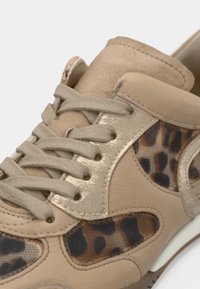 Μπεζ αθλητικό παπούτσι με υφασμάτινα κορδόνια, σουεντ γλώσσα και πάνελ από δίχτυ με λεοπάρ μοτίβο στο πλάι και κοντά στη σόλα.