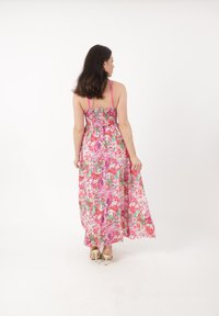 Abito lungo con schiena arricciata, spalline sottili rosa e motivo floreale in rosa, verde e bianco. Tessuto leggero che scorre fino alle caviglie.