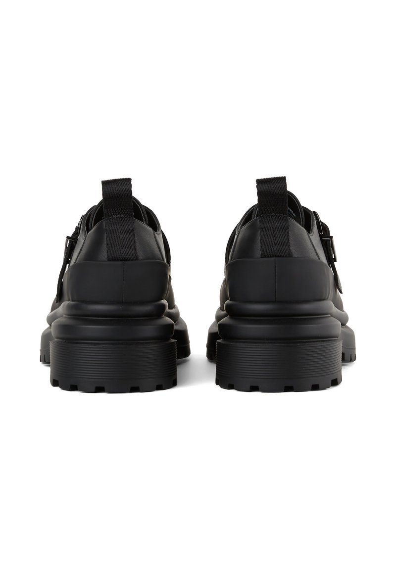 Chaussures en cuir noir avec une semelle épaisse, dotées d'une semelle extérieure en caoutchouc texturé, d'un talon renforcé et de languettes pour un enfilage facile.