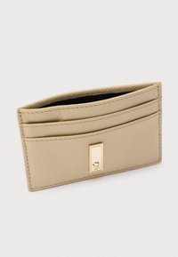 Porta carte in pelle beige con quattro scomparti per carte, una texture liscia e un dettaglio in metallo dorato sul davanti. Design minimalista.