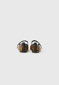 Scarpe slip-on con stampa leopardata, dotate di una cinturino e un accentuazione nera sul tallone. Materiale morbido con forma arrotondata e suola piatta. Vista posteriore mostrata.