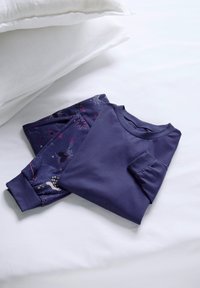 Paarse long-sleeve top met een zak, gevouwen naast bijpassende pyjamabroek met een sterrenpatroon op een lichte achtergrond.