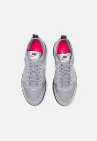 Gray athletic shoes featuring a mesh and suede upper, white logo, pink accents on the interior, and black outsole with textured pattern.
