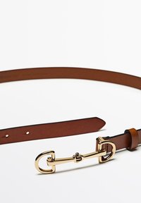 Bruine leren riem met een glanzende gouden metalen gesp met een uniek haakontwerp. Soepele textuur met gelijkmatig verdeelde gaatjes voor aanpassing.