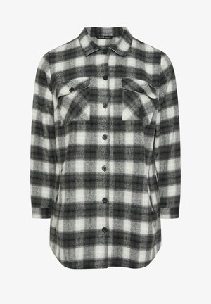 Chemise à carreaux grise et blanche avec des manches longues, deux poches poitrine, un devant boutonné et un ourlet légèrement arrondi. Fabriquée en tissu flanelle.