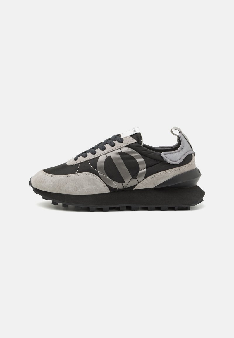 Sneakers featuring black textile and gray suede materials, a rounded toe, black sole, and a prominent logo on the side.