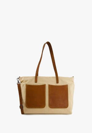 Beige canvas tote bag with two large brown leather front pockets, long leather shoulder strap, and two leather handles.