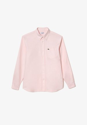 Vaaleanpunainen pitkähihainen nappipaita, joka on valmistettu puuvillasta. Paidassa on kaulus, etutasku ja pieni vihreä logo vasemmassa rinnassa.