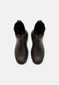 Bottines en cuir marron avec des panneaux élastiques sur les côtés, bout arrondi et semelle en caoutchouc texturé. Petite languette à l'arrière pour un enfilage facile.