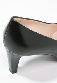 Escarpin en cuir noir avec un bout arrondi, une finition texturée, un talon moyen fin et une doublure intérieure lisse. Design simple, sans décorations.