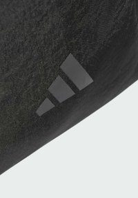 Czarna tkanina tekstylna z wyraźnym szarym logo Adidas i trzema równoległymi paskami. Tekstura wydaje się gładka i lekko błyszcząca.