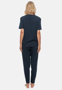 Granatowy zestaw odzieży loungewear z bawełny, składający się z bluzki z krótkim rękawem oraz spodni na elastycznej talii; gładka tekstura, luźny krój.