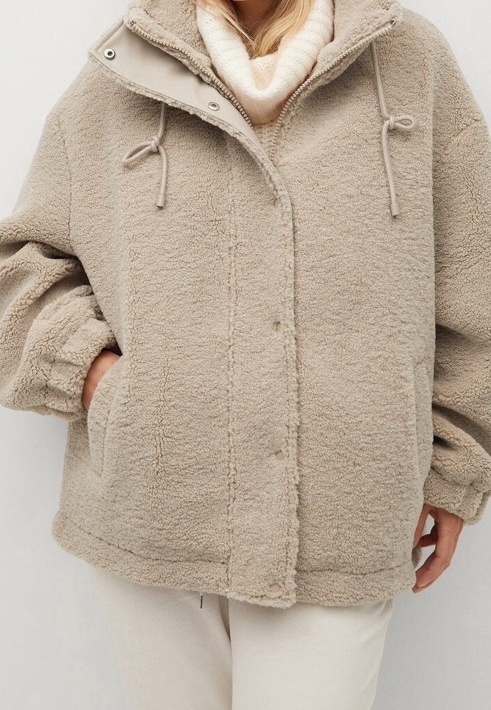 Beige kunstpelsjakke med lynlås og trykknaplukning, med snoretræk, oversized ærmer og sidelommer. Blødt, struktureret stof.