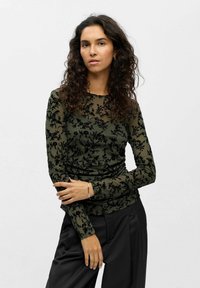 Long-sleeve top in olive green with a sheer floral pattern in black; smooth texture with fitted design and crew neckline.