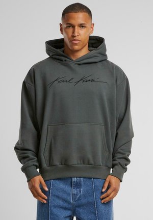 Dark gray hoodie with a front pocket and ribbed cuffs. Features a signature in black across the chest. Soft fabric, relaxed fit.