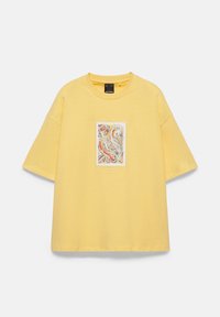 T-shirt jaune oversize à manches courtes avec un petit motif abstrait multicolore centré sur la poitrine.