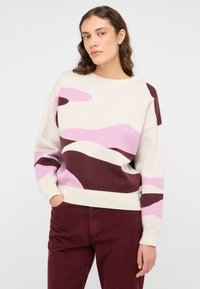 Lichtbeige trui met abstracte patronen in roze en bordeaux, met een ronde halslijn en geribbelde manchetten. Zachte gebreide textuur.