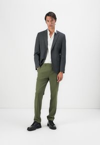 Grau blazer, weißes Hemd, grüne Hose, schwarze Schuhe. Slim-Fit-Design, glattes Material und minimalistisches Styling ohne sichtbare Muster oder Akzente.