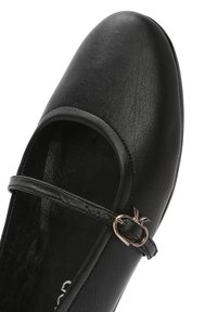 Bailarina negra de piel suave con punta redonda, que presenta una correa delgada y un pequeño acento metálico que recuerda a la forma de una fruta.