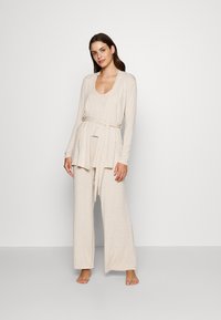 Beige loungewear set featuring a long-sleeve wrap top with a tie at the waist and wide-leg pants, made of soft, comfortable fabric.