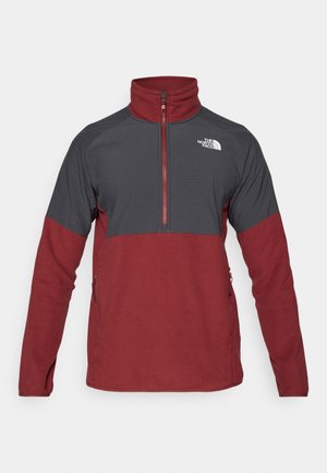 Vörös és szürke polár pulóver, cipzáras nyakkal, amelyen kockás minta található a felső részen, oldalsó zsebekkel és a North Face logójával.
