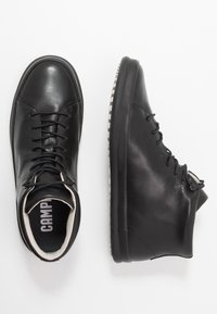 Black leather high-top sneakers featuring a round toe, lace-up design, textured rubber sole, and contrasting white accents on the sole.