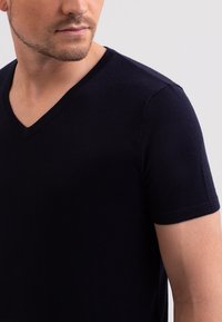 Tmavě modré tričko s krátkým rukávem a výstřihem do V, vyrobené z měkké a hladké tkaniny. Má přiléhavý střih a minimalistický design.